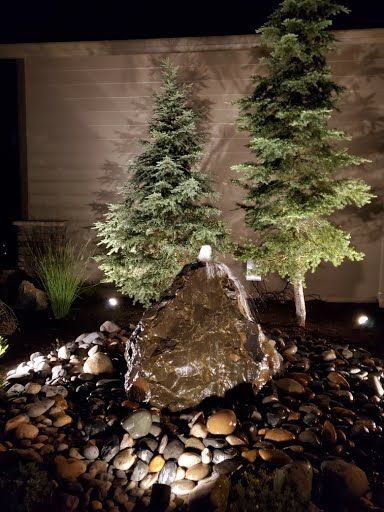 Water feature with uplighting reflecting off stone, Pacific Northwest landscaping