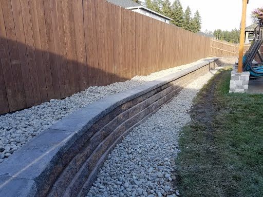 Long retaining wall along property edge with gravel and plantings, Hockinson WA